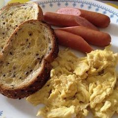 A picture of Scrambled egg with sausages and toasts.