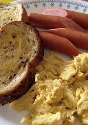A picture of Scrambled egg with sausages and toasts.