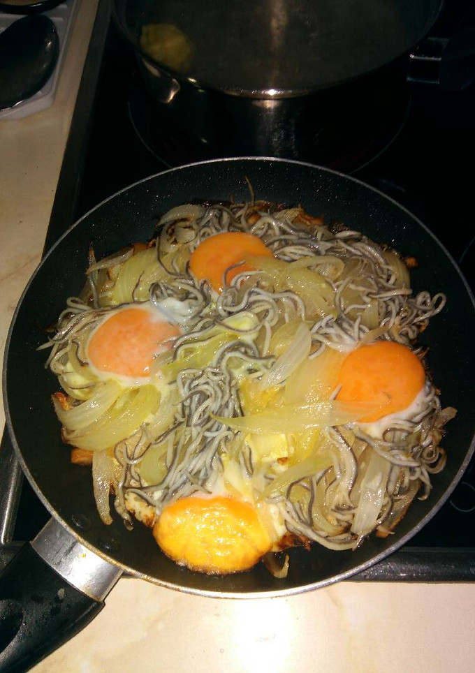 Una foto de Huevos estrellados con gulas, patatas y cebolla