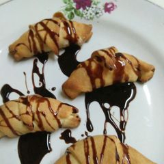 Stuffed dry fruits coconut Croissants drizzled with chocolate sy A picture of Stuffed dry fruits coconut Croissants drizzled with chocolate sy.