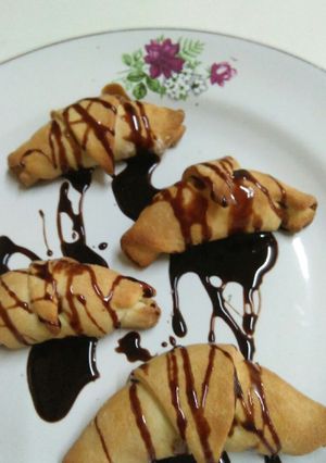 A picture of Stuffed dry fruits coconut Croissants drizzled with chocolate sy.
