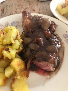 A picture of Lamb steak with red wine and onion sauce.