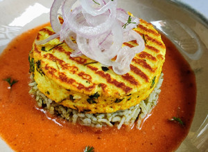 A picture of Paneer Steak on spinach rice with makhani gravy.
