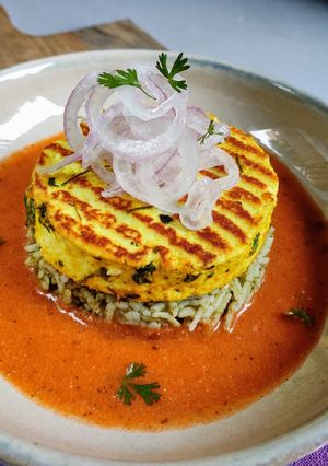 A picture of Paneer Steak on spinach rice with makhani gravy.