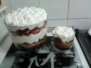 Una foto de brownie con crema y frutillas