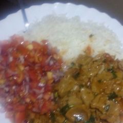 A picture of Beef stew with kachumbari and rice.