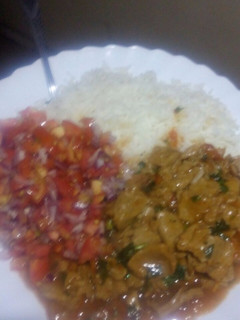A picture of Beef stew with kachumbari and rice.