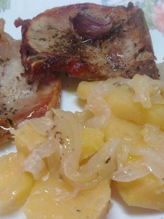 Una foto de Chuletas de cerdo asadas en cama de patatas y cebollas especiadas