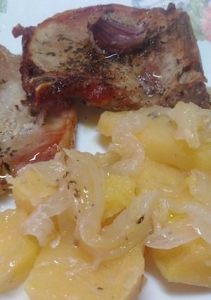 Foto principal de Chuletas de cerdo asadas en cama de patatas y cebollas especiadas