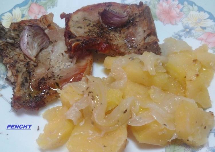 Chuletas de cerdo asadas en cama de patatas y cebollas especiadas