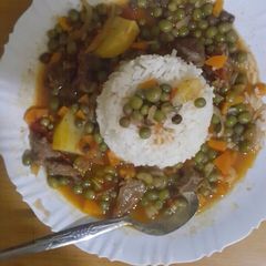 A picture of Boiled rice served with French peas and beef stew.