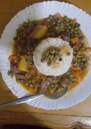 A picture of Boiled rice served with French peas and beef stew.