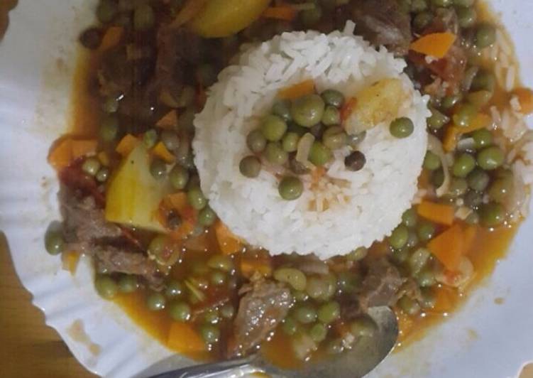 Boiled rice served with French peas and beef stew