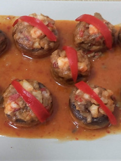 Una foto de Champiñones rellenos de langostinos en salsa picante
