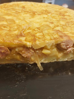 Una foto de Tortilla de patatas con salchichas encebollada al vino