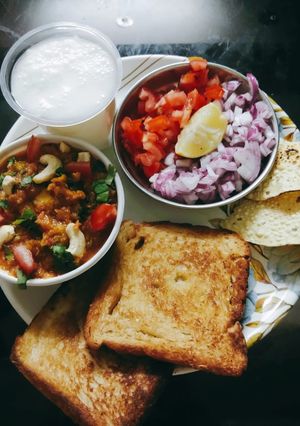 A picture of Pavbhaji with buttermilk papad and salad.