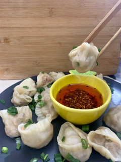 A picture of Dumplings served with chilli oil and soya sauce dipping.