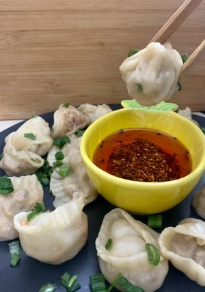A picture of Dumplings served with chilli oil and soya sauce dipping.