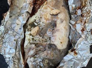 Une photo de Dorades royales en papillote à l ail, citron et persil avec piments grillés