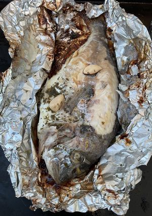 Une photo de Dorades royales en papillote à l ail, citron et persil avec piments grillés
