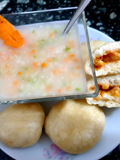A picture of Rice soup with stuffed bun.