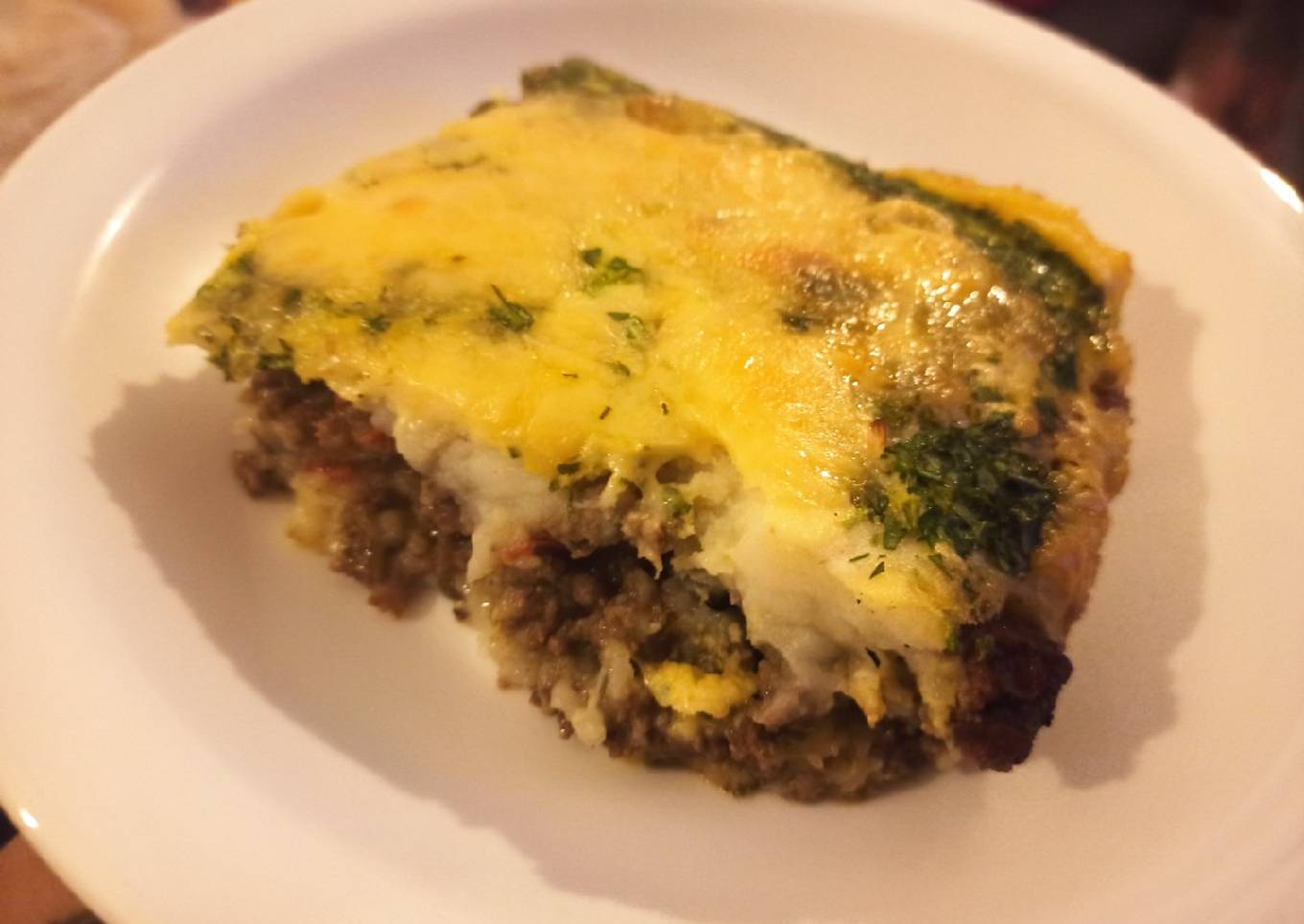 Pastel de carne y papa con costra de queso y perejil