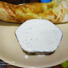 A picture of Masala dosa with coconut chutney.