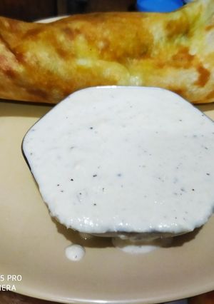 A picture of Masala dosa with coconut chutney.