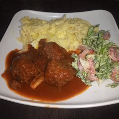 A picture of Mac n cheese with meatballs in sauce & salad.