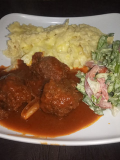 A picture of Mac n cheese with meatballs in sauce & salad.