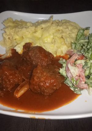 A picture of Mac n cheese with meatballs in sauce & salad.
