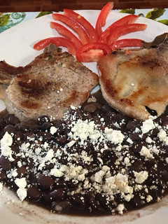 Una foto de Chuletas asadas acompañada con frijoles