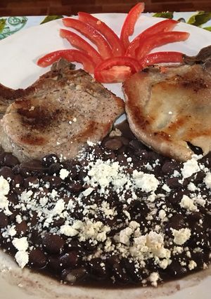 Una foto de Chuletas asadas acompañada con frijoles
