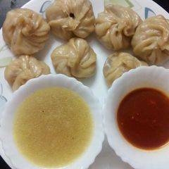 A picture of Chicken momo with soup and chutney.