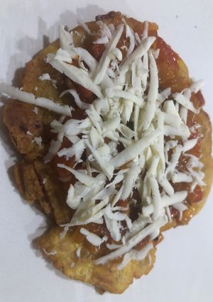 Una foto de Patacones con hogao y queso costeño rallado