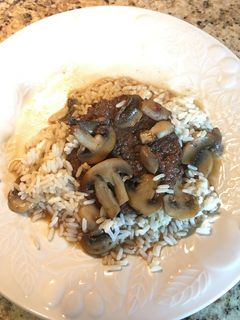A picture of Hamburger Steak with Sautéed Mushrooms on Rice.