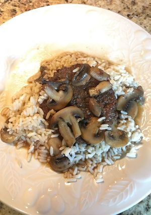 A picture of Hamburger Steak with Sautéed Mushrooms on Rice.