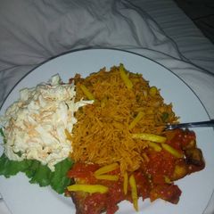 A picture of Jollof rice,coleslaw and fried irish potatoes.