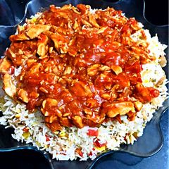 A picture of Red gravy chicken with vegetable rice.