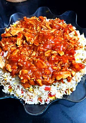 A picture of Red gravy chicken with vegetable rice.