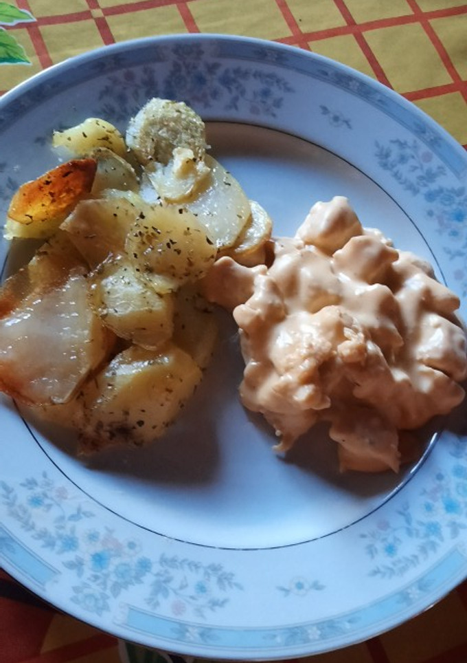 Una foto de Pollo con salsa de queso y papas doradas