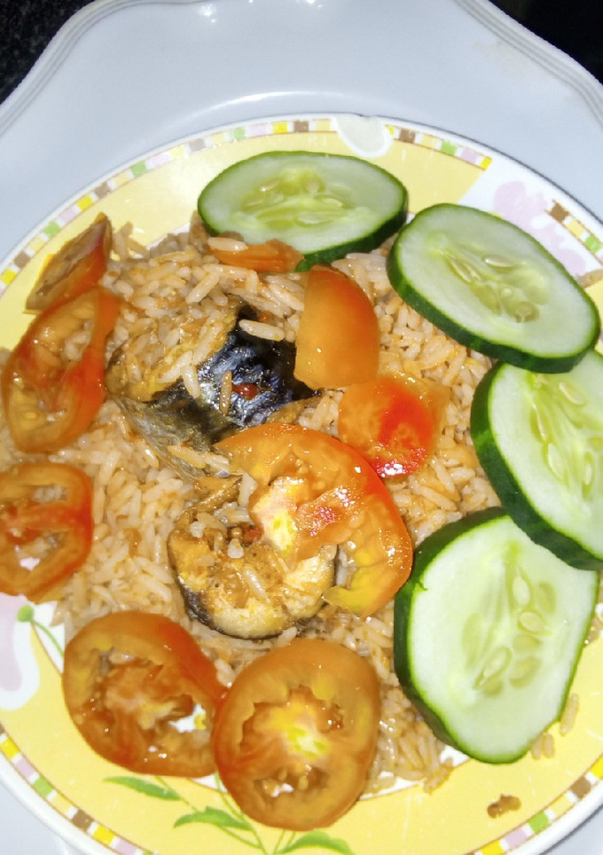 A picture of Jollof rice with sliced cucumbers and fresh tomatoes.
