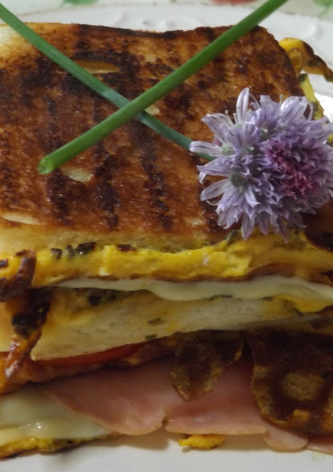 Una foto de Sándwich triple calentito con tortilla de cebollinos