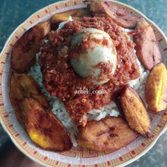 A picture of Rice, plantain, egg sauce and boiled egg.