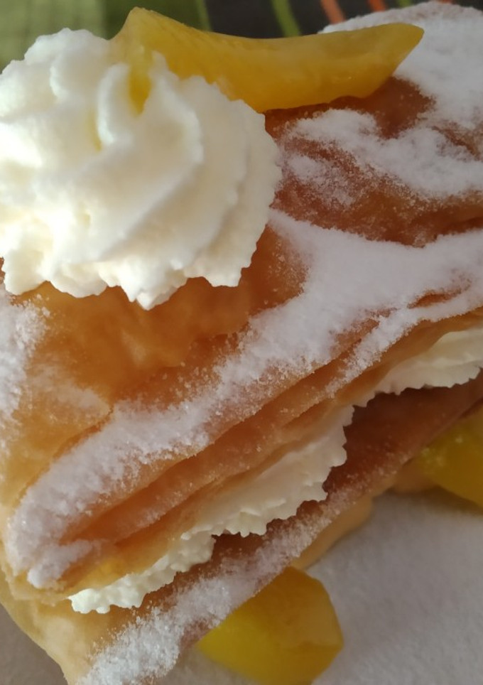 Una foto de Milhojas de pasta filo con crema, melocotones almíbar y nata