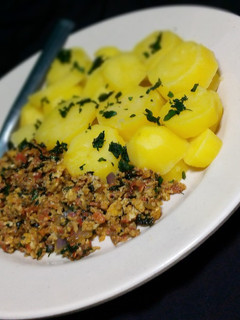 A picture of Garnish boild potato with egg sauce.