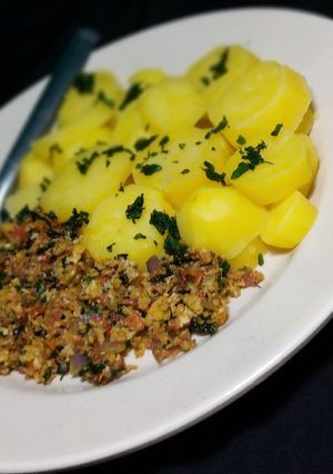 A picture of Garnish boild potato with egg sauce.