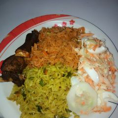 A picture of Fried and jollof rice combo garnished with coleslaw.