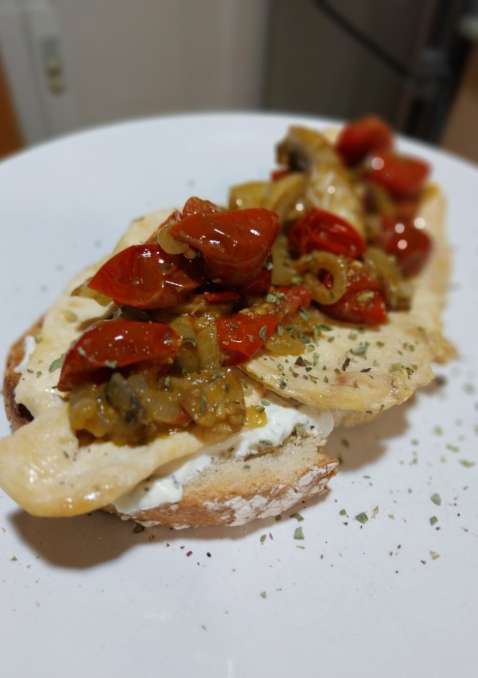 Una foto de Torrada de pollo a la plancha y queso crema con tomate, cebolla y champiñones al pesto