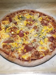 Una foto de Pizza casera de jamón serrano, maíz y cebolla de masa de espelta